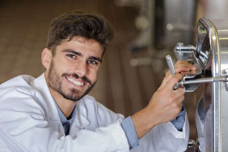 smiling man in uniform working in wine secondary fermentation sectionの写真素材