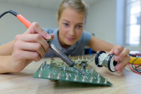 woman assembling works soldering iron