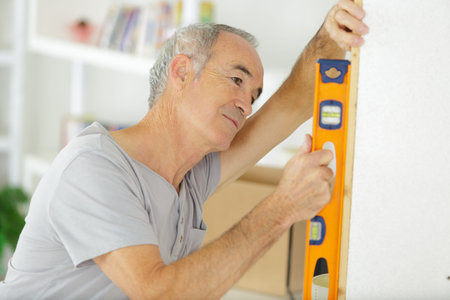 senior man is measuring wall with level