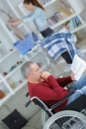 disabled man on wheelchair with help at homeの写真素材