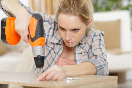 young woman using electronic drill install doorの写真素材