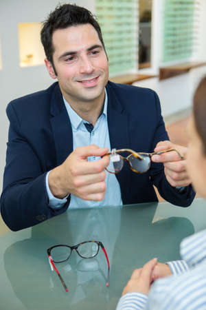 handsome man choosing eyeglasses frame in optical storeの写真素材