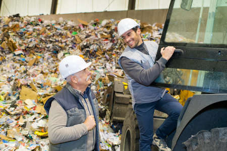 two male workers pointing upwards in recycling centerの写真素材