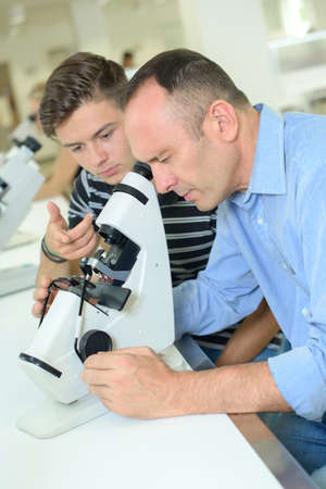 Man looking into eyepiece microscopeの写真素材