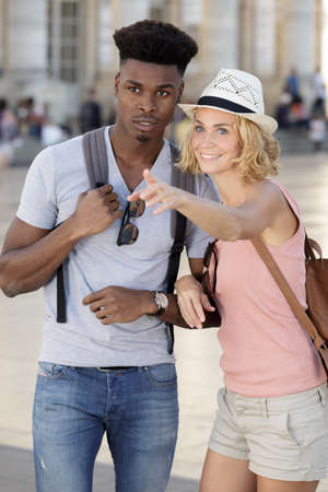 multiethnic couple on city break pointing into distanceの写真素材