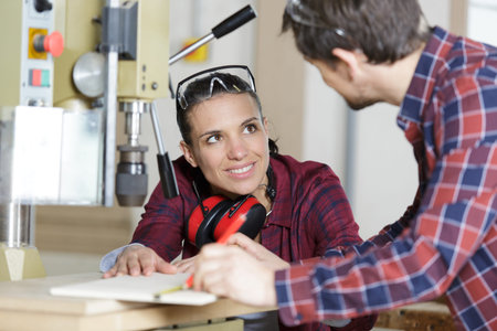 female apprentice talking to colleague in wood workshop