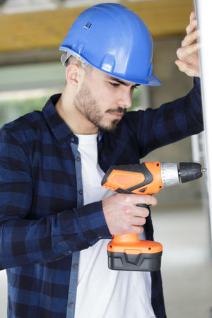 professional builder drilling hole in wall