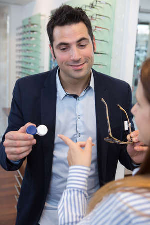 smiling man in optical store buying glasses or lensの写真素材