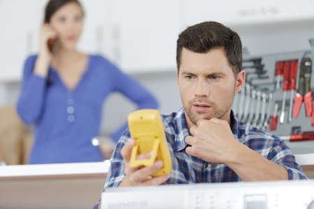 serviceman using multimeter to assess kitchen applianceの写真素材