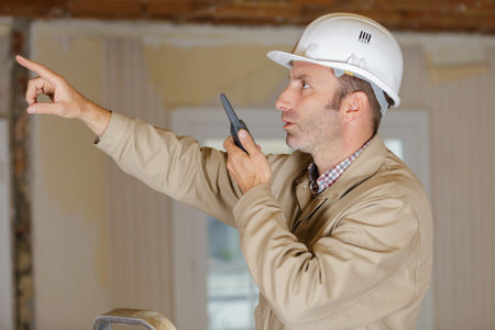 male builder in hardhat with walkie talkie