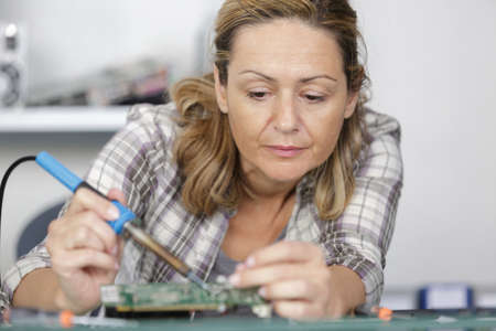 woman soldering elements of circuit boardの写真素材