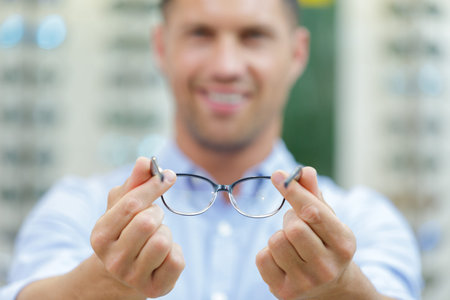 male optician showing pair of eyeglasses