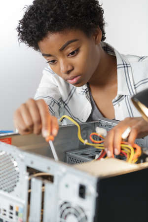 concentrated young woman fixing a desktop computerの写真素材