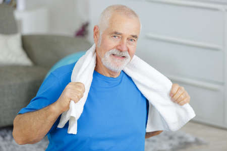 portrait of cheerful senior man in sportswear with towelの写真素材