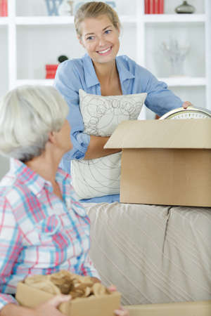 woman holding cardboard box and helping mum unpack thingsの写真素材