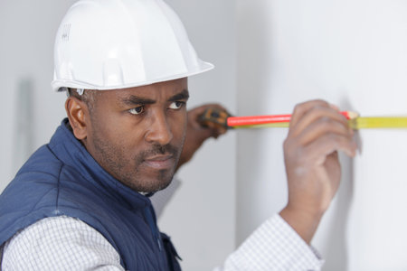 man measuring wall and marking position