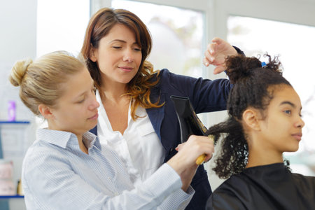 a hairdressing apprentice ironing clients hair