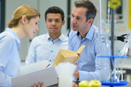teacher showing book to student documenting science experiment