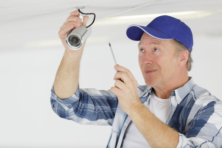 mature man finstalling cctv camera on ceiling