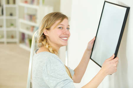 woman hanging blank picture on wallの写真素材