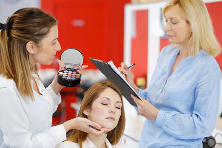 make up artist doing professional make up on young womanの写真素材