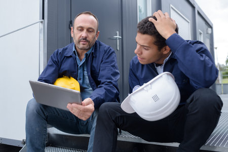 constructor and manager and worker looking at tablet outdoors