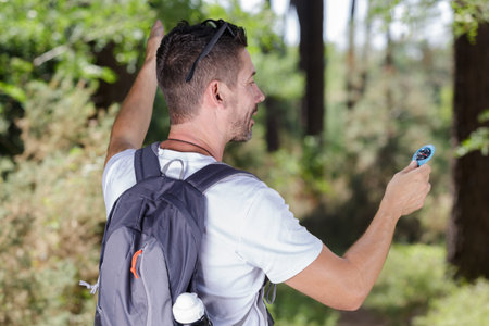 rear view of male backpacker holding compass