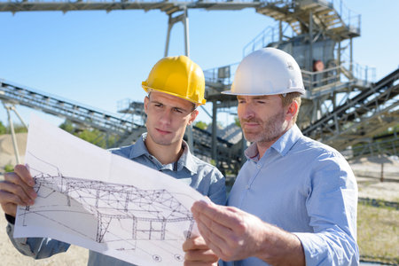 team of builders with construction plan outdoors