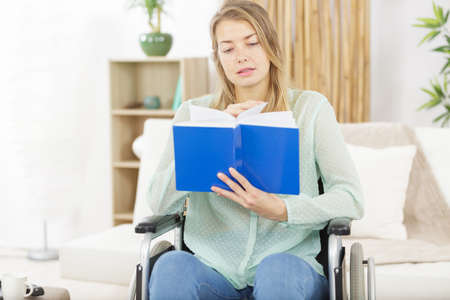 young disabled woman in wheelchair with bookの写真素材