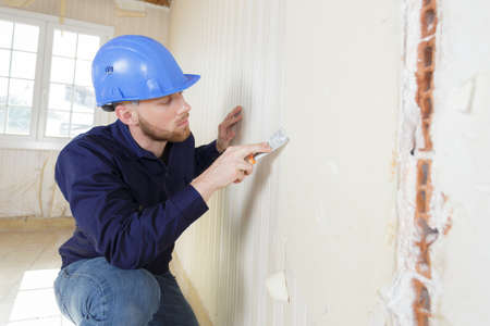 male plasterer in uniform polishing the wallの写真素材