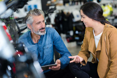 smiling man seller in uniform talking to customerの写真素材