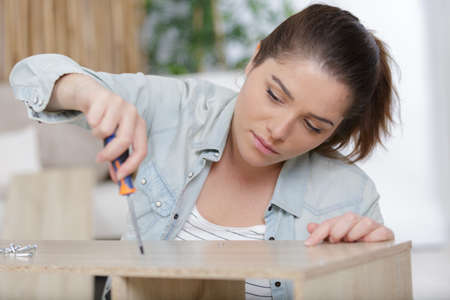 young woman holding screws and furniture partsの写真素材