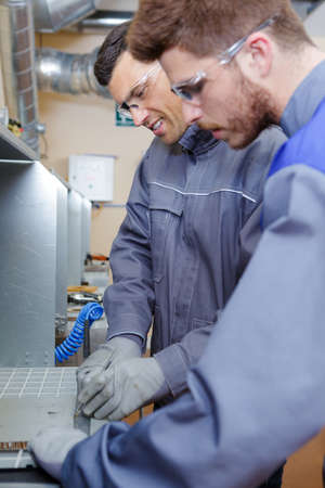 man as apprentice works in teamwork together at metallurgy factoryの写真素材