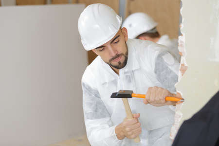 young male builder using hammer and chiselの写真素材