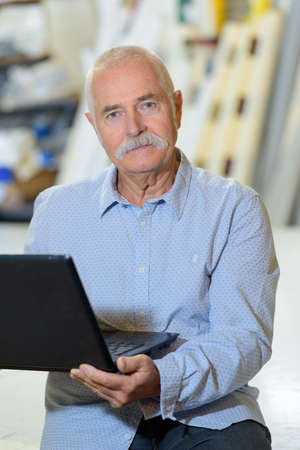 portrait of senior man holding open laptopの写真素材
