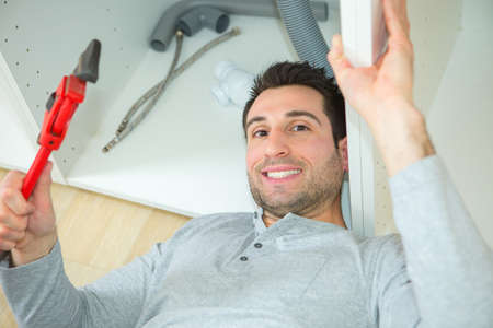 plumber working on sink in bathroomの写真素材