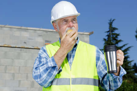 senior engineer builder having a coffee break at construction siteの写真素材