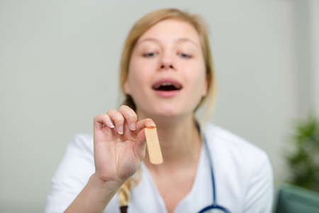 woman doctor examining a throat with spatulaの写真素材