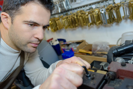 worker cutting duplicates of keys in workshop