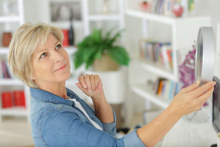 mature woman deciding where to hang her wall clockの写真素材