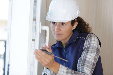 woman builder working using a screwdriver and fix the doorの写真素材