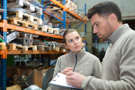 portrait of manager showing a clipboard to worker in warehouseの写真素材
