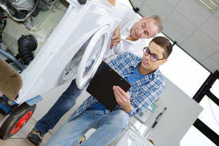 Repairman looking at washing machine on sack trucksの写真素材