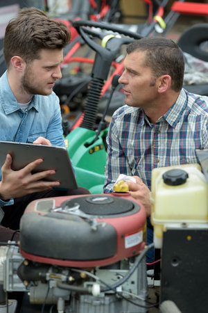agricultural mechanic with trainee holding tablet
