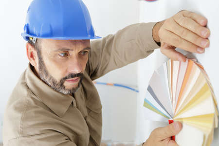 male designer holding colour chart against the wallの写真素材