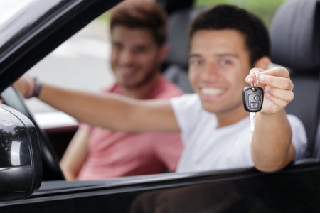 handsome young man with the key inside a new car