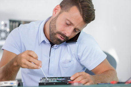 man on the phone while fixing a pc