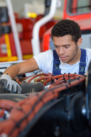 young male mechanic working on fire engine