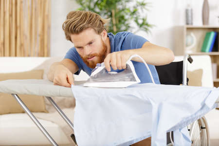 disabled man in wheelchair ironing clothingの写真素材