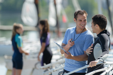 man on wetsuit talking to trainer